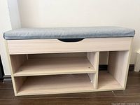 Front view of light wood shoe bench showing cushioned top, open shelves, and drawer.