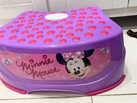 Step stool showing Minnie Mouse graphic on purple plastic with pink non-slip dots on the top surface.