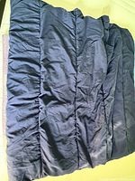 Photo of a navy blue comforter laid out with visible quilted sections and folds in the polyester fabric.