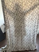 Full view of the neutral abstract patterned polyester blanket hanging vertically, showing the linear vertical design in neutral tones.