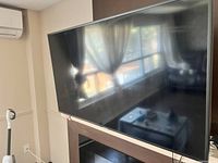 Samsung flat-screen TV turned off showing window reflection