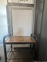 Front view of the hall tree showcasing wooden seat, metal frame, and hooks.