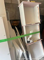 Disassembled storage compartments and shelving units in white and purple, part of the loft bed storage and workspace.