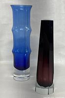 Photo showing two vases side by side, blue vase on right, purple vase on left