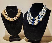 Two multi-strand boho style necklaces displayed on black necklace stands showing overall appearance and size difference.