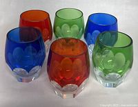 Photo shows six vintage crystal liquor glasses in different colors (blue, red, green, orange) arranged in two rows on a plain white background.