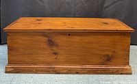 Front view of the closed antique pine blanket chest showing wood grain and knots on the warm honey finish surface.