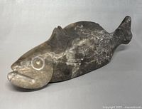 Front left angled view showing carved eyes, mouth, and fin details with some wear.