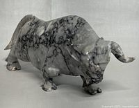 Front side view of the gray and white veined marble bull figurine showing detailed carving and smooth polished texture.
