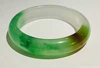 Natural Asian jade D-shaped bangle showing smooth finish and mixed green/white colors