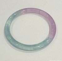 Top view of natural Asian jade bangle showing the lavender to green color gradient with polished glossy surface.