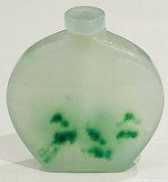 Front view of a pale translucent green jade snuff bottle with darker green jade inclusions inside.