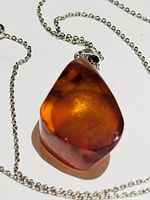 Close-up photo of amber pendant on sterling silver chain showing color and details of pendant.