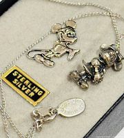 Close-up of Mickey Mouse pin, Minnie Mouse necklace, and sterling silver mark label