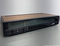 Front and side view showing entire Telefunken Opus HiFi 7050 receiver with wood grain top panel and multiple control sliders, knobs, and FM tuning display.