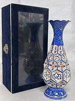 Front view of the enamel vase with its display box in the background.