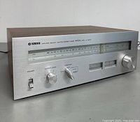 Front side angled view of Yamaha CT-610 stereo tuner, showing power switch, output level knob, function selector, meters, and tuning dial with wooden sides.