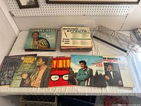 Top view of assorted vinyl records including Johnny Nash, Charley Pride, Dean Martin, Elvis Presley and Mickey Gilley, laid out side by side, showing album covers.