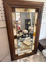 Front view of the rectangular mirror featuring wood frame and floral decorative glass panels surrounding the mirror plate.