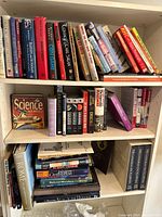 Photo showing three shelves filled with assorted books including science, history, quizzes and more.