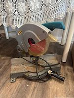 Side view of Makita miter saw showing the blade, guard, handle, and base with rust.
