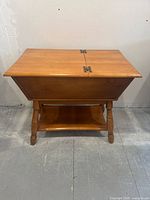 Front view of wooden dough box end table with hinged lid and turned legs.