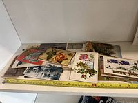 Wide view of the collection of old postcards laid out showing varied designs including floral and architectural images.