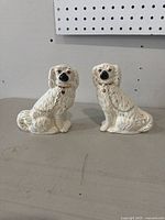 Pair of white Staffordshire style pottery spaniel figurines side by side showing size and details