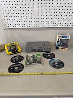 Overview of PlayStation console, Call of Duty discs, electronic handheld game, and boxed Funko Pop figure on shelf.