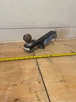 Side view of Reese 2-inch ball mount trailer hitch showing wear and measuring tape for size reference