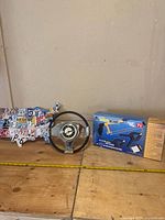 View of the entire lot showing the USA map license plate sign, steering wheel clock, and Total Blade cutter box arranged on a wooden surface.