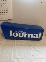 View of blue rectangular mailbox with "The Ottawa Journal" white logo on the side.