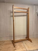 Full view of the towel quilt rack standing on wooden floor against wall.