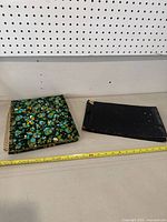 Two old photo albums displayed on a table; one with a colorful floral pattern cover and spiral binding, the other with a plain black worn cover.