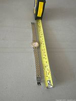 Full length photo of vintage Birks watch next to measuring tape showing approximate length of 18 cm.