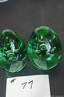 Front view of both green art glass paperweights showing bubble inclusions