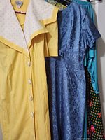 Front view showing yellow dress with polka-dot collar, blue jacquard dress, teal dress and multicolour print dress