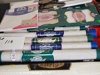 Stack of sealed Aida fabric tubes and flat packs, showing Charles Craft labels and counts
