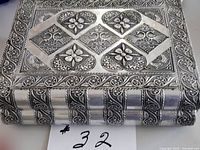 Top view of silver-tone metal jewelry box showing embossed floral and geometric design