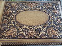 Front cover showing embossed floral and leaf border and blank central panel