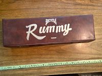 Top view of brown rectangular carrying case with 'Bicycle Rummy' logo in silver lettering.