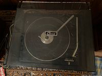 Top view of Garrard 2025 T turntable with dust cover showing platter, tonearm and brand logo.