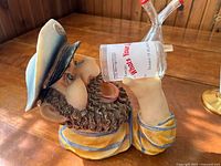 Side view of sailor figurine showing blue and white hat, beard, and glass labeled "What's Your Limit?"