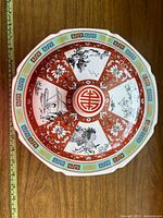 Top view of the ceramic serving dish showcasing the intricate red and white Oriental design with central emblem and scenic panels.