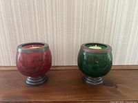 Front view of the red and green crackled glass nautical candle holders with metal bases and rims, each containing a white candle.