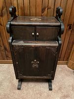 Front view of vintage dark wood smoking cabinet with fleur-de-lis motif and two drawers on top.