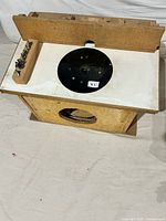 Wooden router table with black router mounting plate, fenced back edge, and side holder with router bits visible on left.