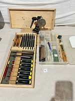 Overall view of carving tools including Footprint carving chisels and gouges in wooden case, Lee Valley carver's vise, rasps and sharpening supplies in containers