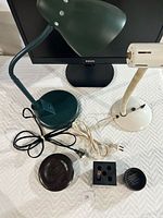 Two desk lamps, black Philips 24-inch monitor, wooden paper clip bowl, wooden coaster, black pen holder and small black bowl.