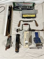 Full view of tools laid out including planes, vise, clamp, socket sets, brace, scale, and draw cutter.
